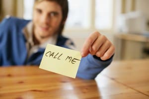 Man holding a note that reads 'call me'